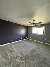 Carpeted empty room featuring a ceiling fan and a textured ceiling
