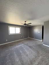 Carpeted spare room featuring a textured ceiling and ceiling fan