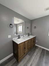 Full bath featuring double vanity, dark wood-style floors, and a textured ceiling