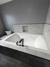 Bathroom featuring a jetted tub and toilet