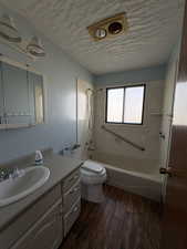 Full bathroom featuring shower / bathtub combination, vanity, dark wood-style floors, and a textured ceiling