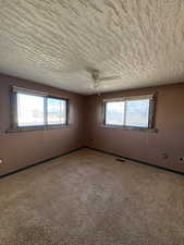 Carpeted spare room featuring healthy amount of natural light and ceiling fan