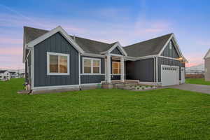 Modern farmhouse featuring board and batten siding, roof with shingles, driveway, and a lawn