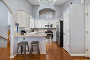 Kitchen with stainless steel appliances, light countertops, white cabinetry, a breakfast bar, and a peninsula