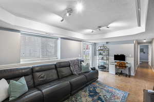 Living area featuring an office area, a textured ceiling, rail lighting, tile patterned flooring, and a wainscoted wall
