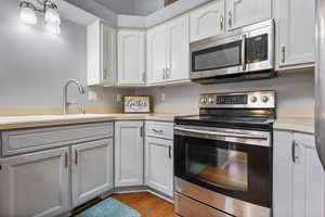 Kitchen featuring appliances with stainless steel finishes, light countertops, white cabinets, and light wood-style flooring