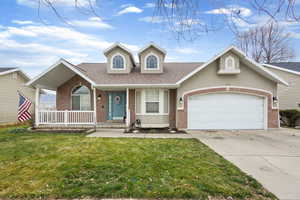 Traditional home with a shingled roof, a porch, a front lawn, brick siding, and concrete driveway