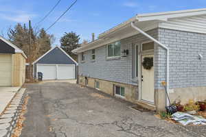 View of home's exterior with brick siding, an outbuilding, and a garage