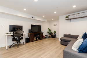 Living room with recessed lighting, light wood finished floors, and a desk