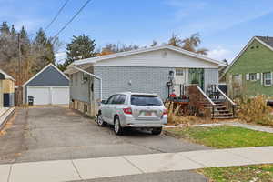 View of front of home with brick siding, a garage, and an outbuilding