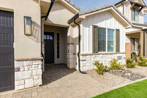 View of exterior entry with stone siding, board and batten siding, and stucco siding