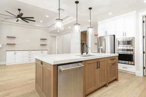 Kitchen with a center island with sink, open shelves, white cabinets, brown cabinetry, and appliances with stainless steel finishes
