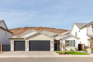 View of front of home with stone siding, decorative driveway, an attached garage, and board and batten siding