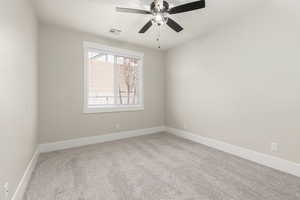 Empty room featuring light colored carpet and a ceiling fan