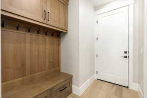 Mudroom featuring light wood-style flooring and baseboards