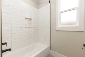 Bathroom featuring shower / tub combination and baseboards