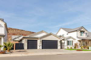 Modern farmhouse featuring concrete driveway, a garage, stucco siding, and stone siding