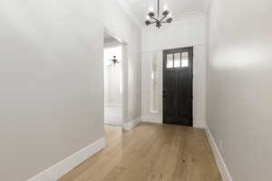 Entrance foyer featuring light wood finished floors, a chandelier, and a ceiling fan