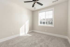 Carpeted empty room featuring baseboards and a ceiling fan