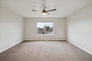 Carpeted spare room featuring baseboards and a ceiling fan