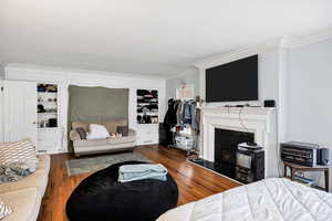 Living room featuring crown molding, a fireplace, hardwood currently used as a bdrm.