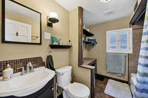 Full bathroom featuring tasteful backsplash, vanity, stone finish floors, and shower / bath combo