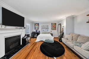 Living room featuring crown molding, a fireplace, hardwood currently used as a bdrm.