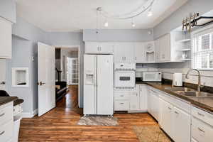 Kitchen with white appliances, white cabinetry, open shelves, and dark wood-style flooring