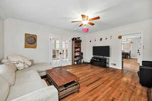 Living room featuring hardwood / wood-style flooring, healthy amount of natural light, ornamental molding, ceiling fan, and french doors