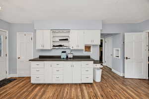Kitchen featuring open shelves, dark countertops, and white cabinetry