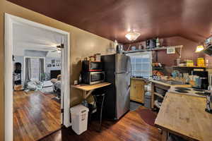 Kitchenette on upper floor featuring lofted ceiling, appliances with stainless steel finishes, dark wood-type flooring, butcher block countertops, and open shelves
