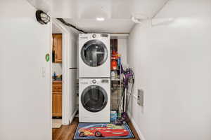 Laundry room featuring stacked washer / drying machine and wood finished floors