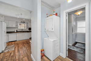 Washroom with stacked washer and clothes dryer, dark wood-type flooring, and a textured ceiling