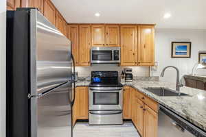 Kitchen featuring light stone counters, appliances with stainless steel finishes, light wood-type flooring, and recessed lighting