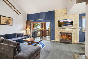 Living room featuring carpet, a tile fireplace, and high vaulted ceiling