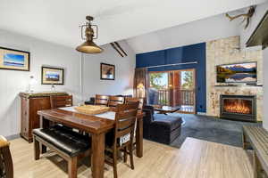 Dining space featuring a stone fireplace, lofted ceiling, and light wood finished floors