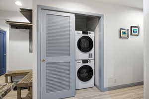 Laundry room featuring light wood-style flooring and estacked washer and dryer