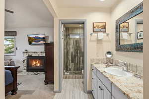 Full bathroom with vanity, a stall shower, a glass covered fireplace, and light wood-style floors
