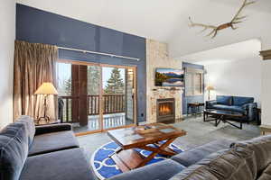 Living area with a fireplace, carpet floors, and high vaulted ceiling