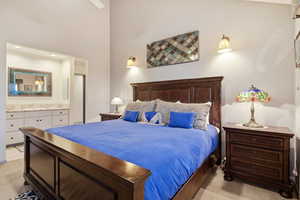 Bedroom featuring light colored carpet, a towering ceiling, and ensuite bathroom