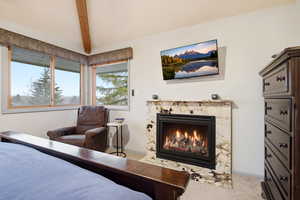 Carpeted bedroom with a fireplace and baseboards