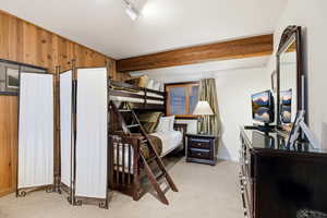 Bedroom featuring light carpet and wooden walls