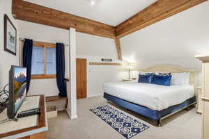 Bedroom with beam ceiling and light carpet