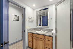 Bathroom featuring vanity, a stall shower, light wood finished floors, and recessed lighting