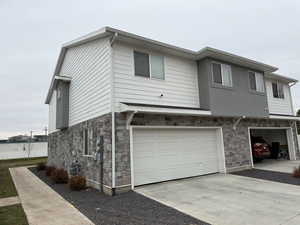 View of front facade with stone siding, concrete driveway, and an attached garage