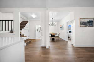Foyer entrance with light wood-style floors, stairs, and a chandelier