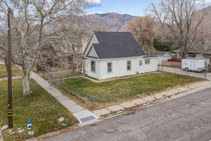 View of front of house with a fenced front yard, a shingled roof, and a mountain view