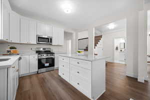 Kitchen featuring white cabinetry, appliances with stainless steel finishes, and dark wood finished floors