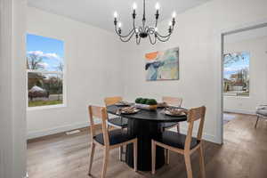 Dining area with wood finished floors, a chandelier, and plenty of natural light