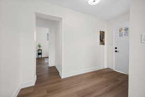 Hall with dark wood-style flooring and baseboards